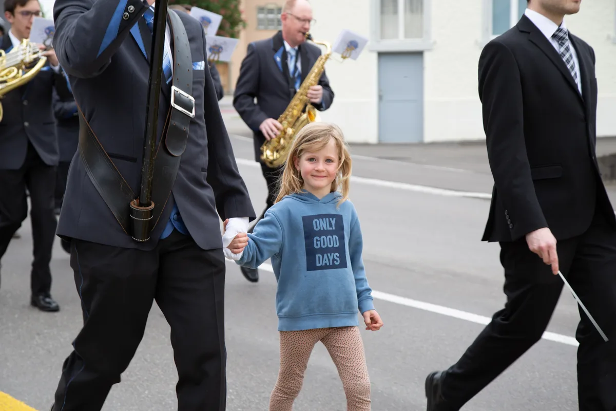 Grosse Ehre: Dieses Mädchen durfte den Fahnenträger begleiten. Man sieht ein kleines Mädchen, das die Hand eines Mannes hält. uM IHR SIND MAN mUSIKER.